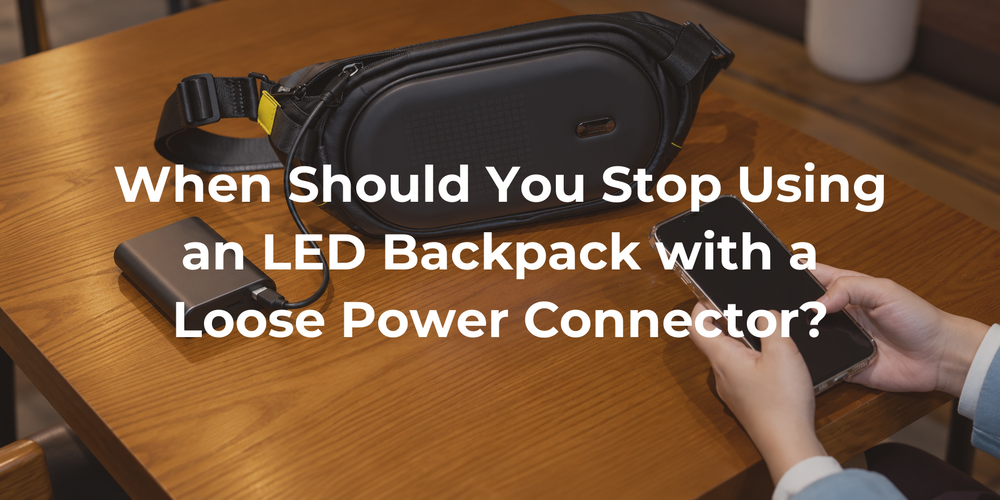 The supplied black LED sling bag on a wood table beside an external power connection.