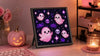 Pink Halloween pixel art desk setup with Divoom Pixoo-64 showing cute pink ghosts