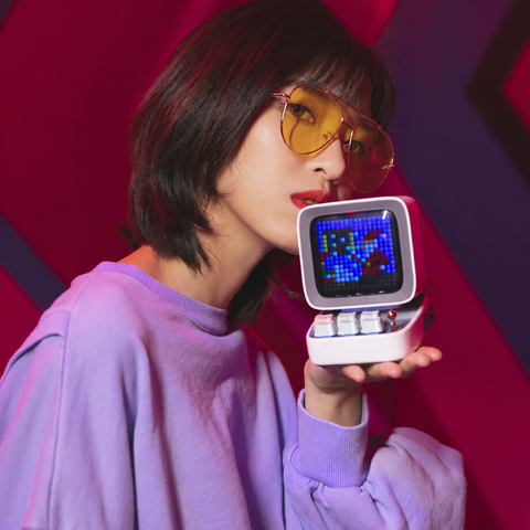 Woman holding a white Divoom Ditoo pixel art speaker
